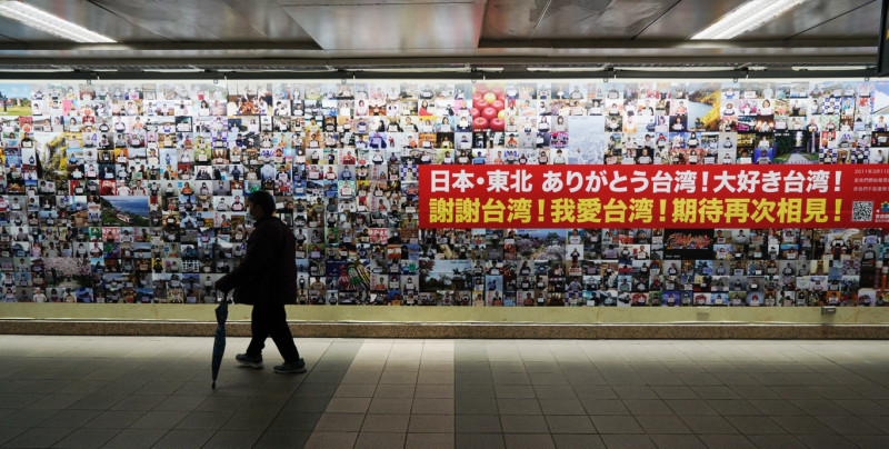 一位民眾經過展示日本東北民眾感謝台灣的照片牆。   圖：張良一/攝