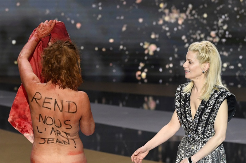 法國女演員馬西洛(Corinne Masiero)有「法國奧斯卡」之稱的凱撒獎在12日的頒獎典禮上，脫光全裸在台上抗議。背部的文字寫著「把藝術還給我們，讓！」   圖:達志影像/美聯社