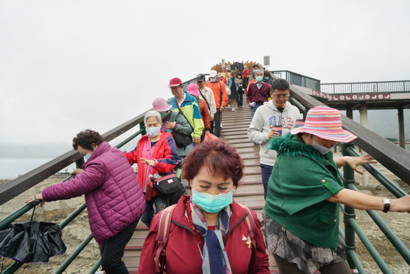 到日月潭觀光的遊客雙手抓著引橋的欄杆一步一步走去登船。   圖：張良一/攝