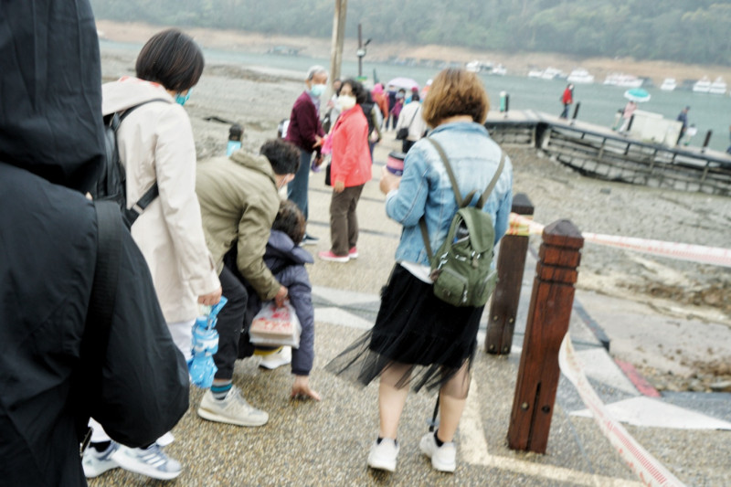 一位遊客往伊達邵碼頭引橋走下去時，由於坡度大加上天雨路滑，走著走著滑倒了，引起同伴一陣尖叫。   圖：張良一/攝