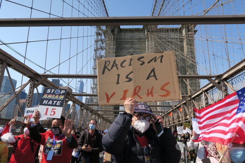 2019冠狀病毒疾病期間仇恨犯罪盛行，紐約上萬民眾當地時間4日遊行呼籲停止仇恨亞裔，示威者在布魯克林大橋上高舉「種族歧視是病毒」標語。   圖/中央社