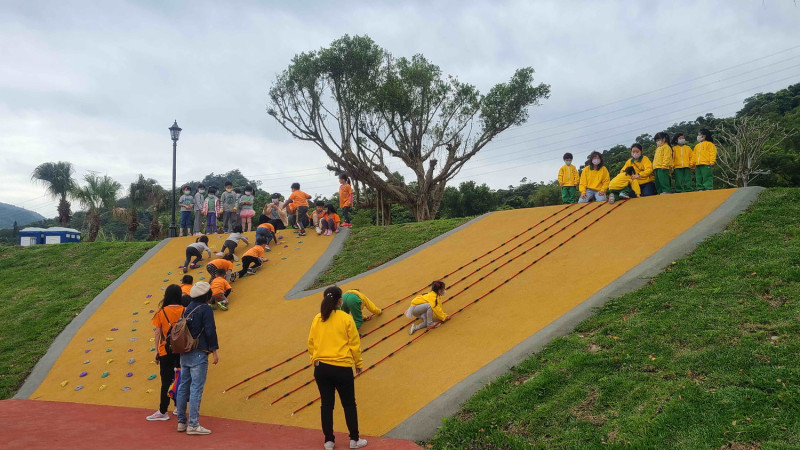 灣潭兒童遊戲場結合既有的綠坡，將蝴蝶翅膀轉化為溜滑梯區及攀爬區。   圖：新北市高灘地工程管理處提供