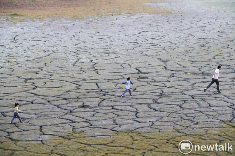 一位爸爸帶著孩子在已然變成日月潭大草原的大竹湖一帶湖底奔跑。   圖：張良一/攝