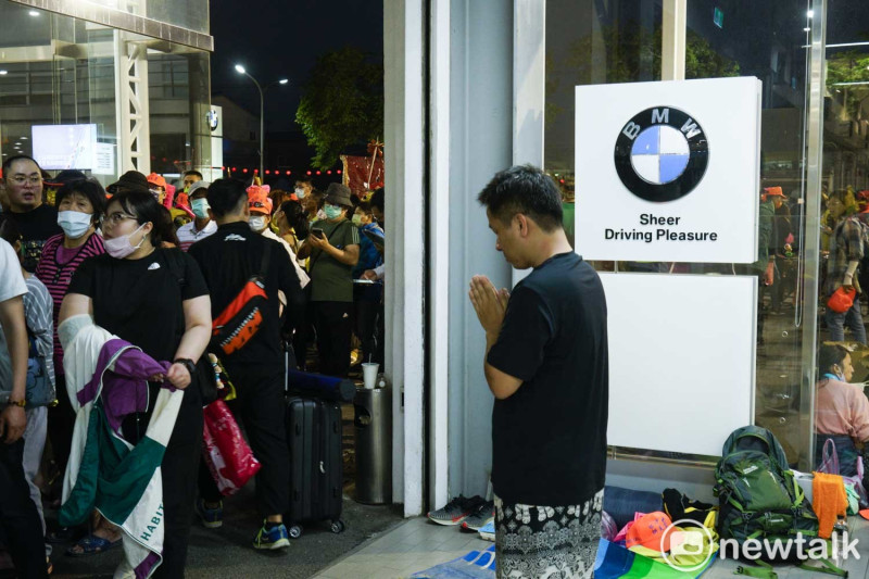 一位進香客在銷售BMW汽車的彰化昌一汽車維修中心內，雙手合十向白沙屯媽祖祈福。   圖：張良一/攝