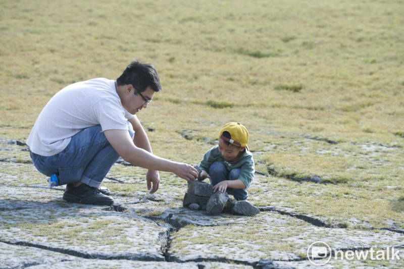 一對父子在「日月潭大草原」把乾涸龜裂的淤泥當作積木玩。   圖：張良一/攝