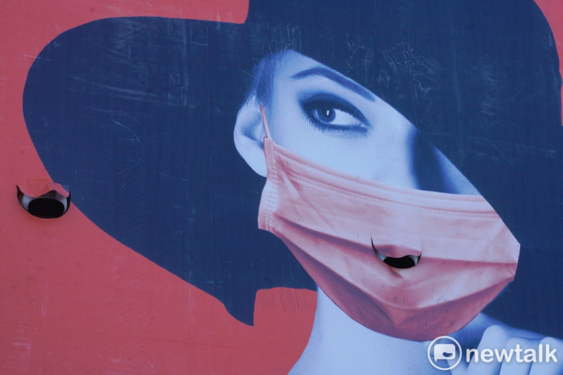 Icu醫生陳志金分享正確的「脫口罩」方式也很重要。圖為萬華環河南路一棟建物外的廣告看板，畫面中的口罩正巧破了一個洞。   圖：張良一/攝