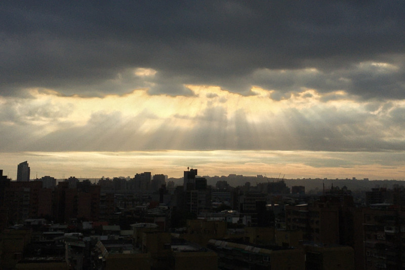 夕陽穿透滿佈烏雲的台北上空灑下「耶穌光」。   圖：張良一/攝