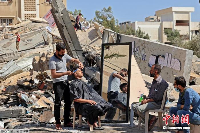 一個巴勒斯坦居民在以色列轟炸過後的廢墟替民眾理髮。(資料照片)   圖 : 翻攝自中新網