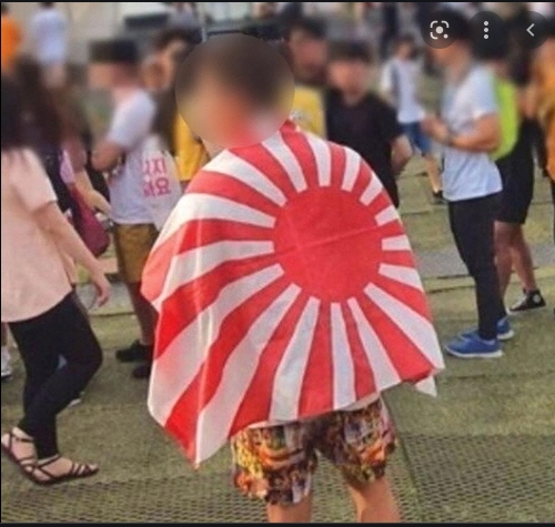 一名日本民眾背上披著象徵軍國主義的旭日旗。(示意圖)   圖 : 翻攝自搜狐