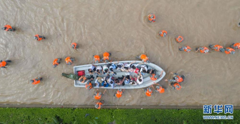 鄭州淹大水後，軍警出動救災，讓居民登上救生船。   圖 : 翻攝自新華網
