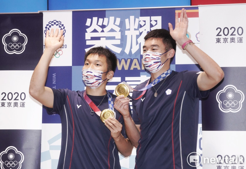 王齊麟（右）、李洋榮耀歸國，手持東京奧運羽球雙打金牌向現場的粉絲們揮手致意。   圖：張良一攝