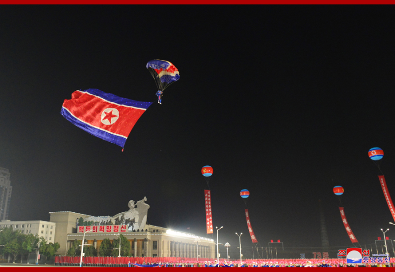 身上懸掛紅白藍三色朝鮮國旗的傘兵在現場展現了跳傘降落特技表演。   圖 : 翻攝自朝中社