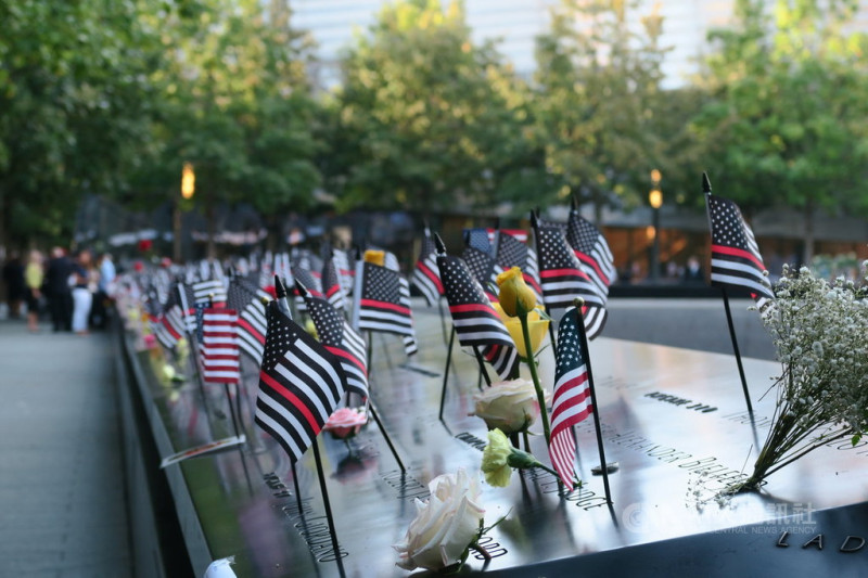 911恐怖攻擊事件20週年，紐約世界貿易中心雙塔遺址刻有罹難者姓名的紀念水池插滿鮮花與小型星條旗。   圖/中央社