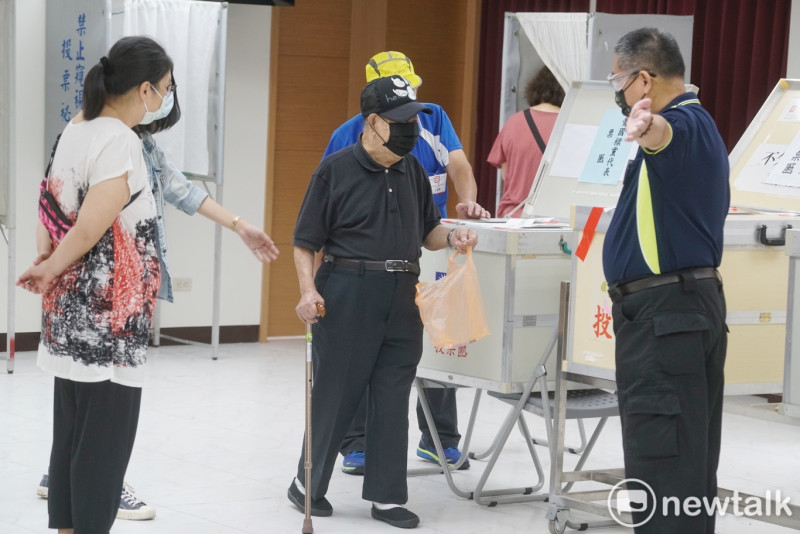 一位拄著拐杖的老黨員在工作人員的協助下投票。   圖：張良一/攝