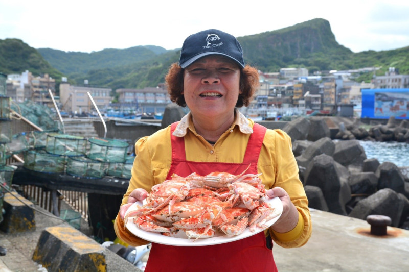 假日市集的媽媽手持剛蒸好的萬里蟹，鮮甜可口（非疫情時拍攝）。   圖：新北市漁業及漁港事業管理處提供