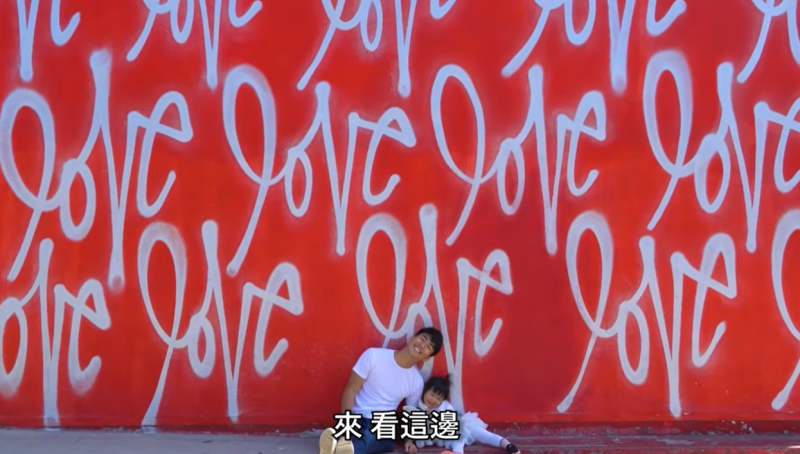 Maddy和Ian在寫滿「Love」的紅色網美牆合照。   圖：翻攝自 The DoDo Men YouTube頻道