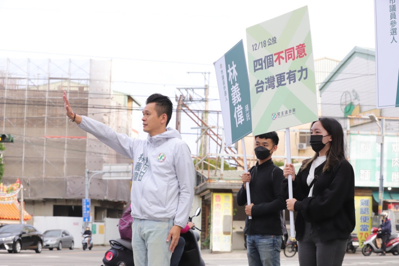 民進黨新人林義偉在大雅區昌平、雅潭五叉路口，舉起「四個不同意，台灣更有力」標語，呼籲民眾在12月18日的公投，投下四個不同意票。   林義偉/提供
