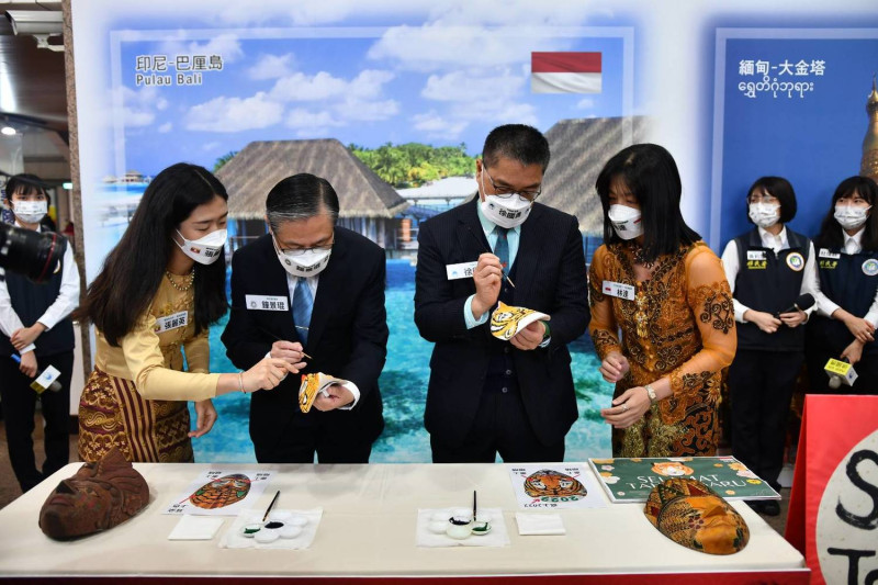 在印尼新住民林達的引導下，移民署長鐘景琨彩繪虎面的印尼傳統面具。圖：內政部提供