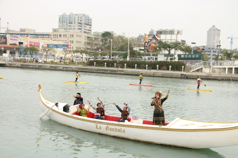 國際午宴中，知名的魯凱族歌手金秀麗乘坐愛河貢多拉船，在8位著各國國旗裝的立槳手帶隊下，在河上演唱。   圖：高雄市政府提供
