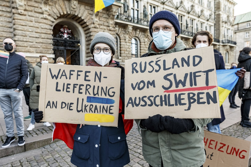 烏克蘭聲援示威中的兩名抗議者舉著標語，上面寫著“向烏克蘭提供武器供應”和“將俄羅斯排除在 SWIFT 之外”。   圖/達志影像(美聯社)