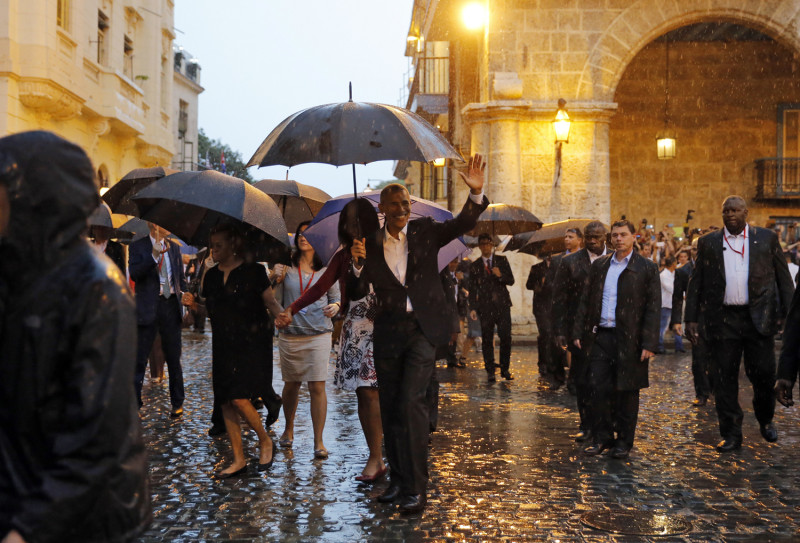 美國總統歐巴馬（中，揮手者）攜第一夫人蜜雪兒在雨中踏上古巴哈瓦那舊城，開心向古巴支持民眾揮手致意。   圖：達志影像/路透社