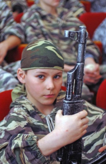 俄羅斯女童身穿迷彩軍服，手持AK-47。   圖：翻攝俄新社