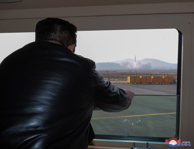 北韓領導人金正恩透過窗戶視察「火星-17」型洲際飛彈試射。   圖：翻攝自朝中社