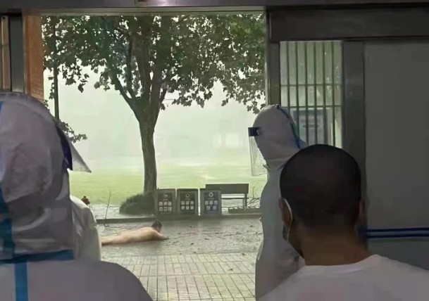 一名住在方艙醫院的男子在淋浴時，淋浴間整間被暴風吹走，讓他狼狽趴在地上被圍觀拍攝。   圖：翻攝推特