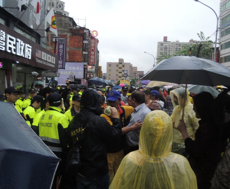 冒雨抗議的民眾高喊「日本走狗、滾回日本」的口號，甚至向「台灣民政府」台北州板橋辦事處丟雞蛋，一度還有人大喊警察打人、「衝進去！」。   圖：陳冠廷/攝