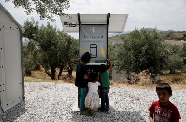孩子們圍繞在太陽能行動裝置充電站旁。設置於希臘列斯伏斯島卡拉泰佩市立難民營中的太陽能充電站，是由一群大學生所設計的。   圖：達志影像/路透社