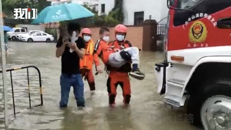 在湍急水流下，消防人員更需一把將婦幼扛起涉水，將市民帶往鄰近醫院避難。   圖：截自《新京報》