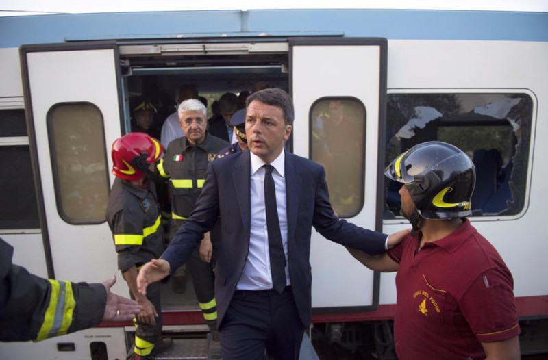 義大利總理倫奇（中）趕赴事故現場，為救難人員打氣，背後的火車車廂車窗全破。   圖：翻攝倫奇臉書