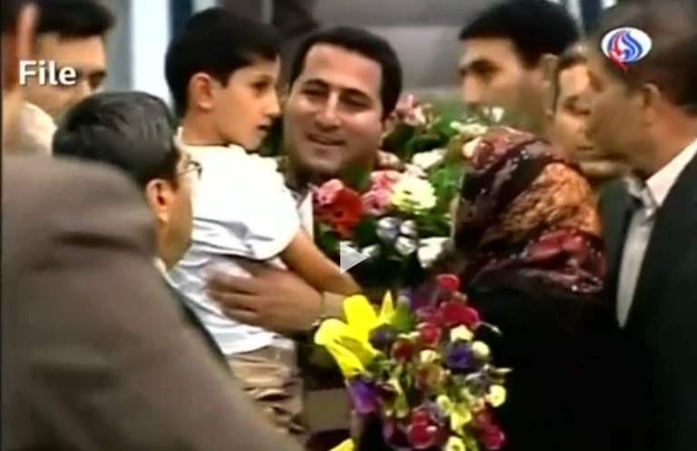 伊朗核子科學家阿米里（中抱小孩者）一度失蹤，在2010年回到伊朗首都德黑蘭時，受到英雄式歡迎。   圖：翻攝《The Sydney Morning Herald》影片
