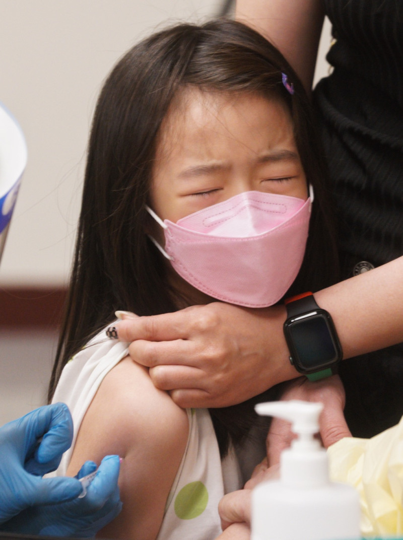 一位小朋友接種新冠肺炎疫苗時，她的眼睛瞇著，痛得不禁流出眼淚來。   圖：張良一/攝