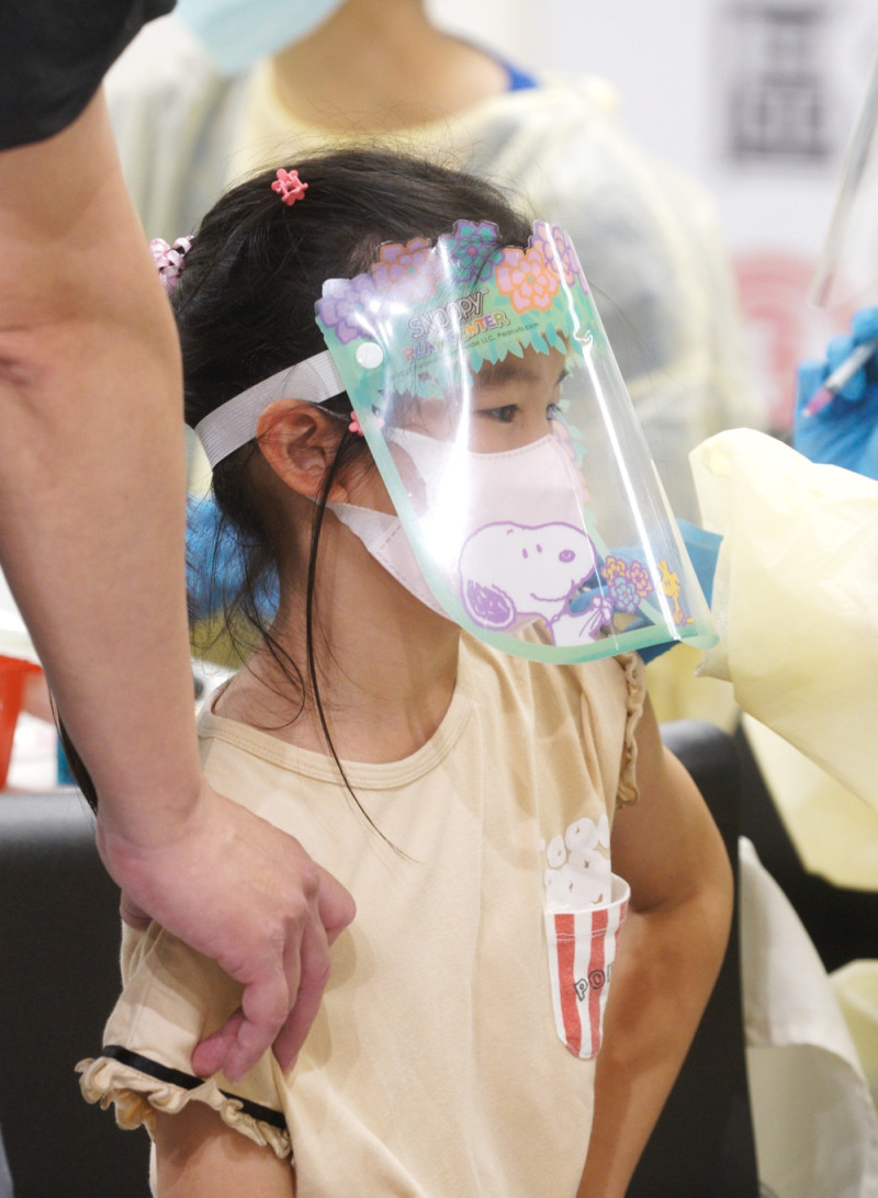 一位戴著護目面具的小朋鎮定的接受護理人員為她接種新冠肺炎疫苗。   圖：張良一/攝