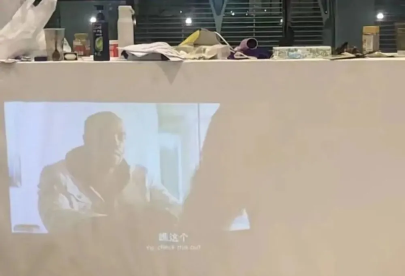 「橋哥」他在浦東機場自備投影機看新聞，以白色床單製成幕布，利用附近散落的椅子擺飾得像客廳似的。 圖：擷自「騰訊網」