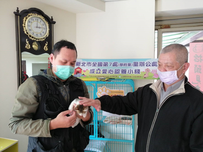 淡水區學府里長林文成 (右)向里民林勝宗介紹貓咪，成功完成認養。   圖：新北市動保處提供