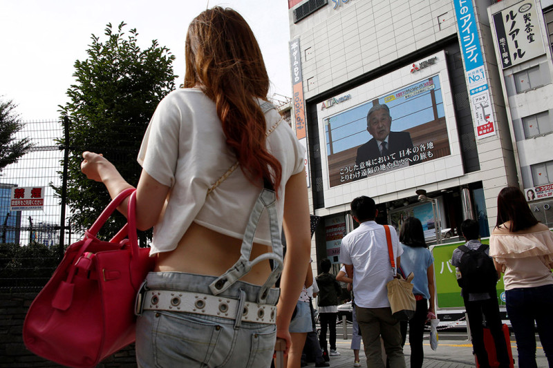 東京民眾8日下午在街頭觀看日本天皇明仁的電視講話。   圖：達志影像/路透社