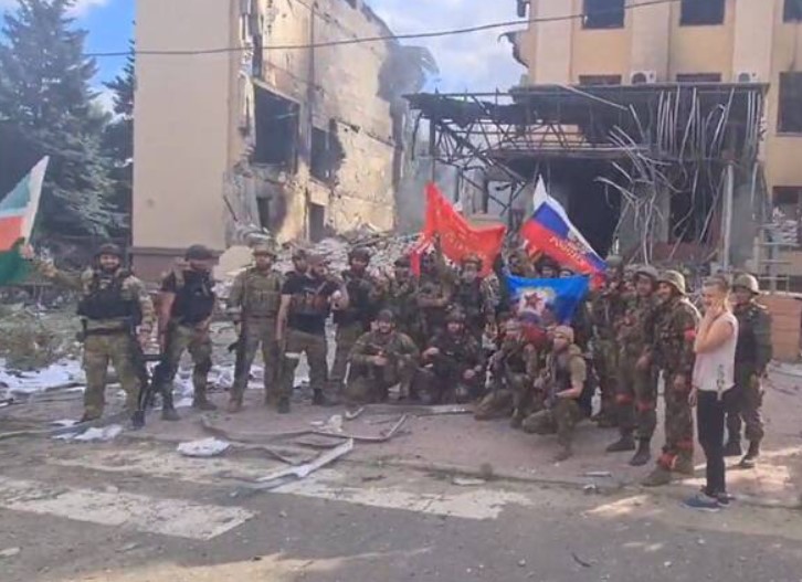 俄國入侵烏克蘭，車臣也出兵相助。數名車臣士兵在利西昌斯克被摧毀的行政大樓前揮舞蘇俄國旗。   圖：翻攝自推特