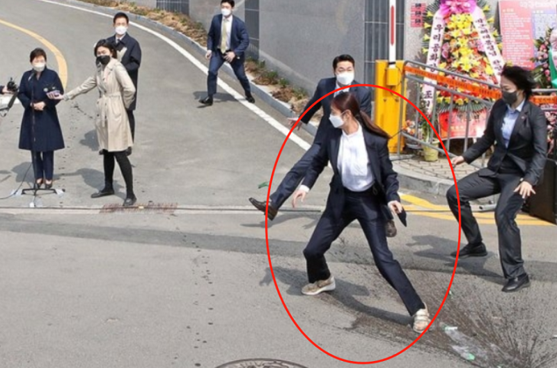 韓國前總統朴槿惠在公開談話遭襲，女保鏢飛身擋著酒瓶。   圖：翻攝自海外網