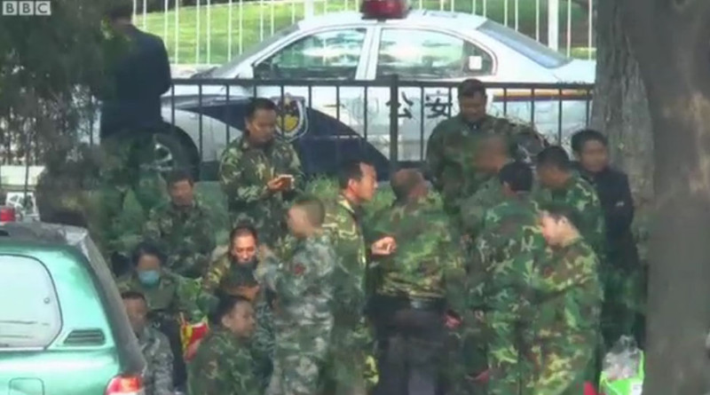 中國退伍軍人穿著迷彩裝，聚集在八一大樓外，他們拒絕受訪，英國BBC記者只能遠距離拍攝。   圖：翻攝BBC