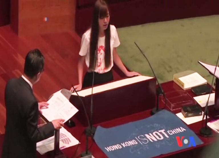 香港新科立法會議員游蕙禎（右）拿出英文寫的「香港不是中國」的藍色布條，進行宣誓。   圖：翻攝美國之音