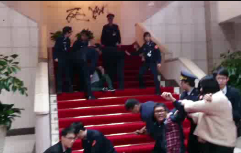 國民黨工18日下午衝進行政院大廳，並於敞廳樓梯處用噴漆噴上「死」字，遭警方壓制。   圖：翻攝自民眾拍攝影片