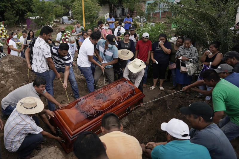 居民將受害者棺材放入坑中，現場氣氛哀傷。   圖：達志影像/美聯社