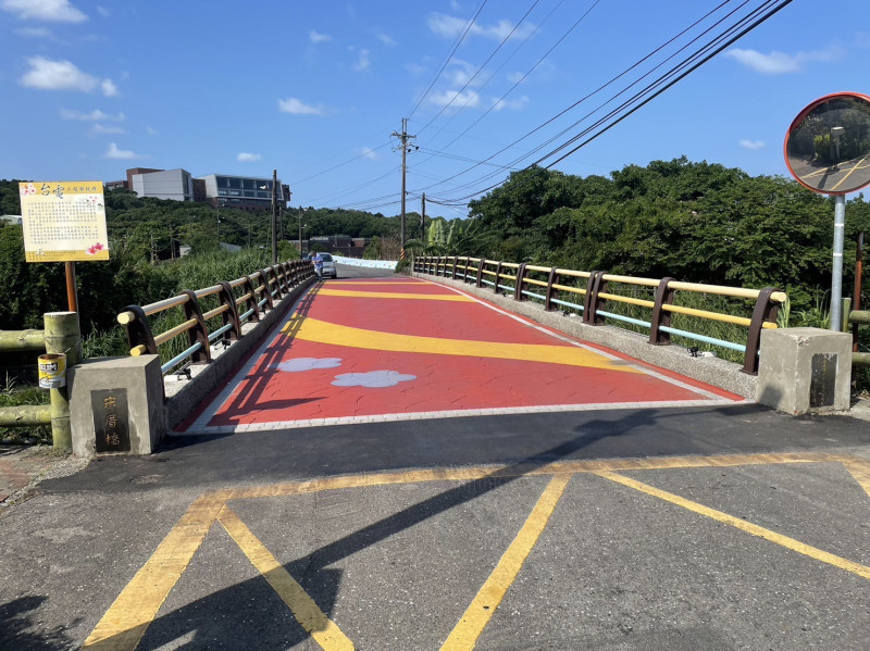 改善後的三芝宋厝橋，橋梁欄杆以不同顏色油漆搭配，增加活潑度；橋面則採用壓印彩色圖樣的瀝青鋪面，平坦又美觀，並設置投射照明燈具，維護原先豐富生態，提升道路安全。   圖：新北市工務局提供