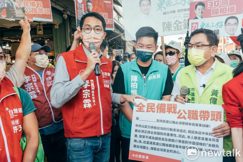 陳柏惟和陳金鐘至後甲黃昏市場聯合拜票時，台灣基進台南黨部主委暨東區市議員參選人李宗霖也出面迎接過去在台灣基進的老戰友陳柏惟，給予深情的擁抱，並提出「全民備戰，公職帶頭」的承諾書請兩人簽署。   圖：黃博郎／攝