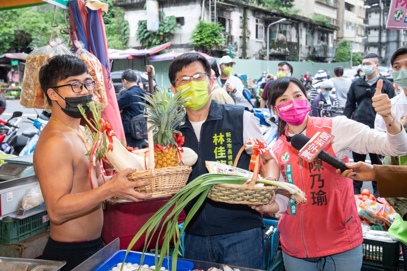 林佳龍在新北市議員候選人陳乃瑜等人陪同下到新店建國、仁愛市場掃街拜票，攤商預祝他凍蒜。   圖：林佳龍競辦提供