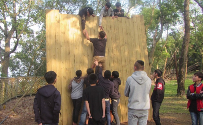 學員們同心協力，協助隊友爬過高牆。   圖：台中市教育局提供