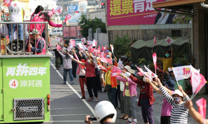 民眾手舉陳其邁的桃紅選舉旗幟在路旁歡迎。   圖：除其邁競總提供