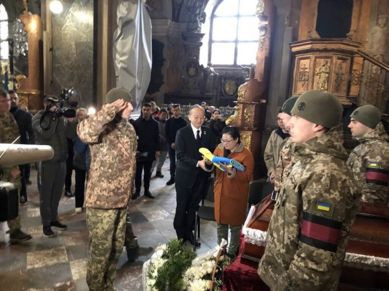 烏克蘭軍方舉辦曾聖光追思儀式，軍方代表向曾聖光致敬，駐波蘭代表陳龍錦（黑色西裝者）陪同家屬。   圖：外交部提供